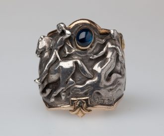 Soffi Drachmann fik lavet denne ring til sin mands 60 års fødselsdag den 9. oktober 1906. Den er tegnet af kunstneren J.F. Willumsen og udført af sølvsmeden Georg Jensen. Motivet er taget fra Drachmanns skuespil 'Hr. Oluf han rider. Den danske sommernats drama'.